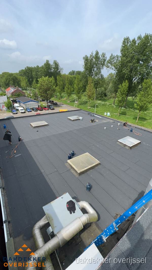Dakdekker aan het werk op groot plat dak met bitumen in Overijssel