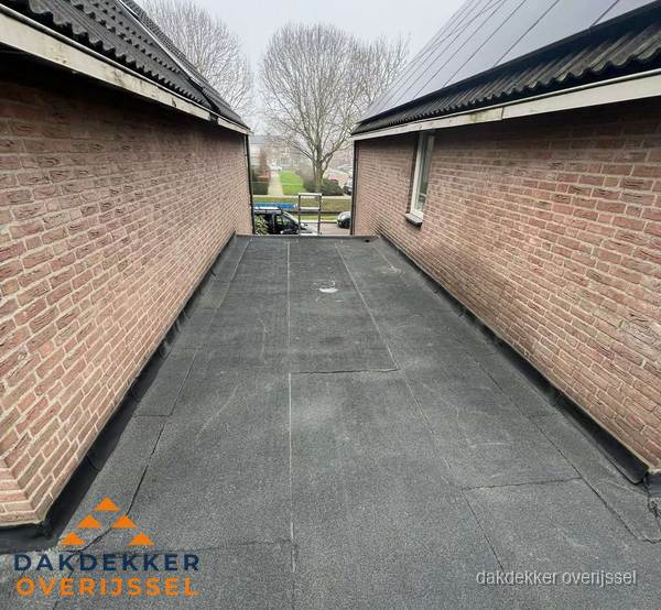 Plat dak met bitumen dakbedekking tussen bakstenen muren in Overijssel