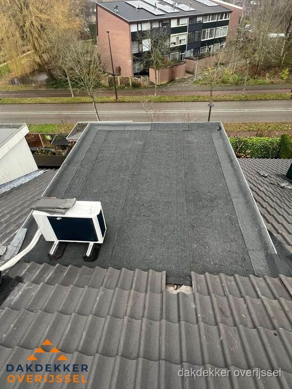 Plat dak inspectie met bitumen bedekking naast schuin pannendak in Overijssel
