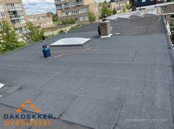 Bitumen dakbedekking op plat dak met lichtkoepel en schoorsteen in Overijssel