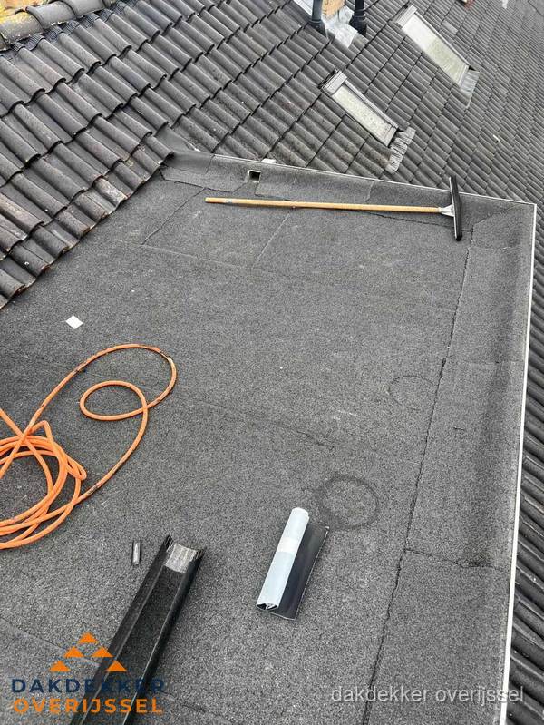 Plat dak reparatie met gereedschap en loodstroken in Overijssel