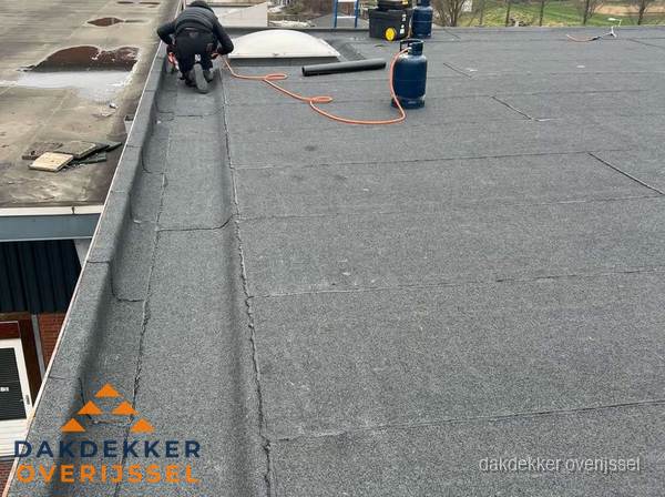 Dakdekker repareert bitumen dakbedekking op groot plat dak in Overijssel